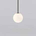 Opal sphere hanging from a short black rod, this Clérachic pendant filling more of the frame on a light grey backdrop.