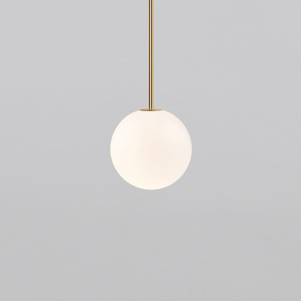 Opal sphere hanging from a short brass rod, this Clérachic pendant on a light grey backdrop.