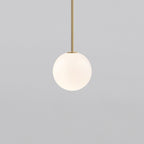 Opal sphere hanging from a short brass rod, this Clérachic pendant on a light grey backdrop.