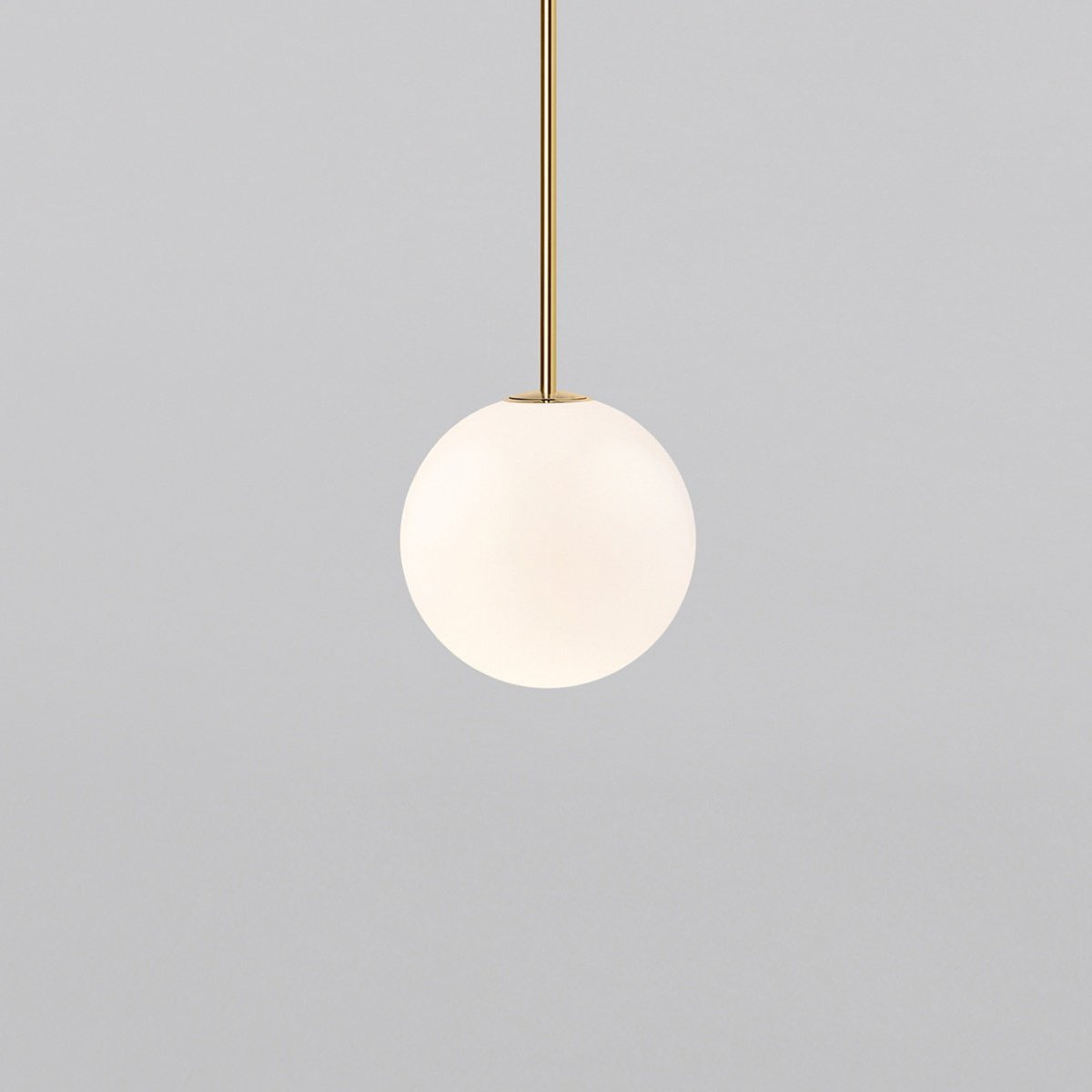 Opal sphere hanging from a short brass rod, this Clérachic pendant on a light grey backdrop.
