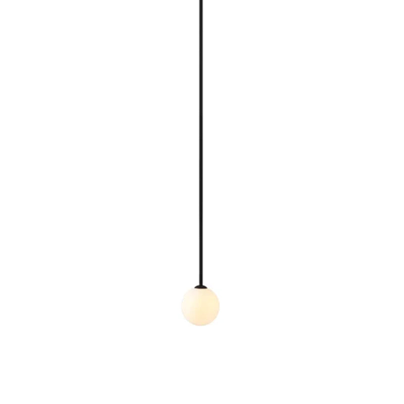Lit opal sphere hanging from a very long black rod, this Clérachic pendant on a white backdrop.