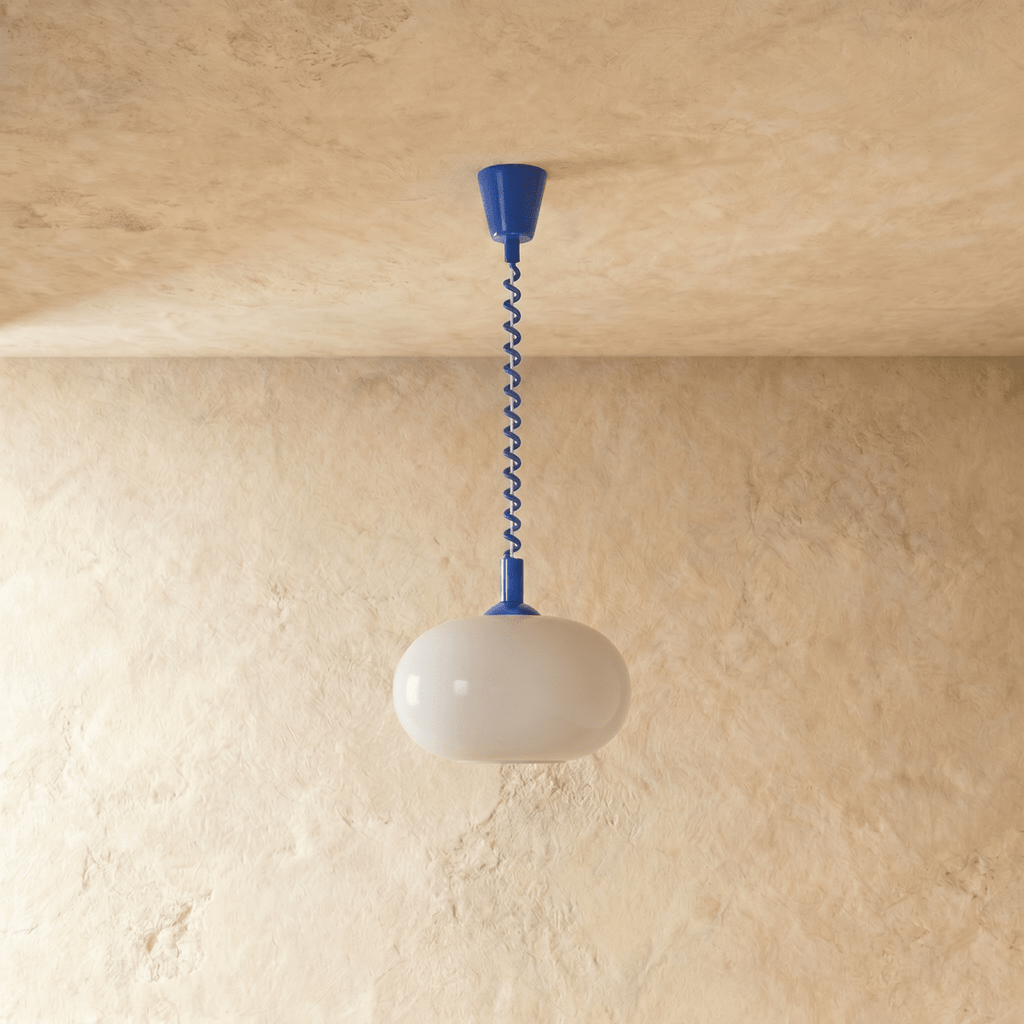 Clérachic pendant with a rounded opal glass shade, unlit, hung from a cobalt blue coiled spring cable and canopy.
