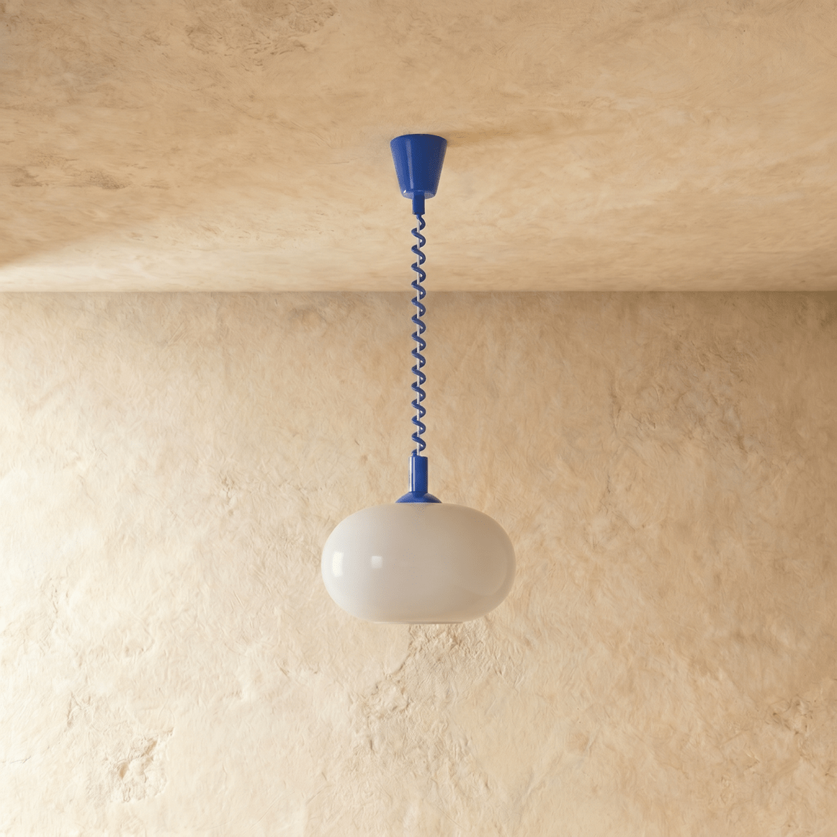 Clérachic pendant with a rounded opal glass shade, unlit, hung from a cobalt blue coiled spring cable and canopy.