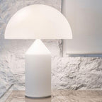 Close view of the matt white glass dome and cylinder base of this Clérachic table lamp, set against rough white plaster.