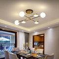 The Clérachic Opal Globe Ceiling Light in its 6-light crossed-arm layout, mounted semi-flush above a dining table with a balcony view beyond.