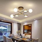 The Clérachic Opal Globe Ceiling Light in its 6-light crossed-arm layout, mounted semi-flush above a dining table with a balcony view beyond.