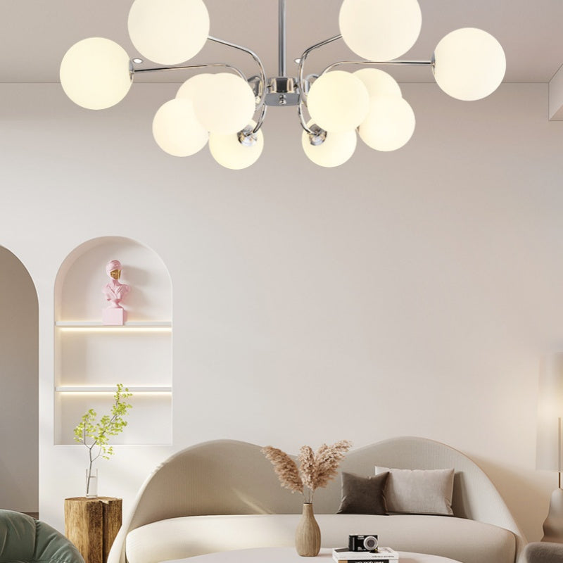 A Clérachic opal-globe sputnik chandelier in polished chrome hangs above a curved sofa and arched display niche in a living room.