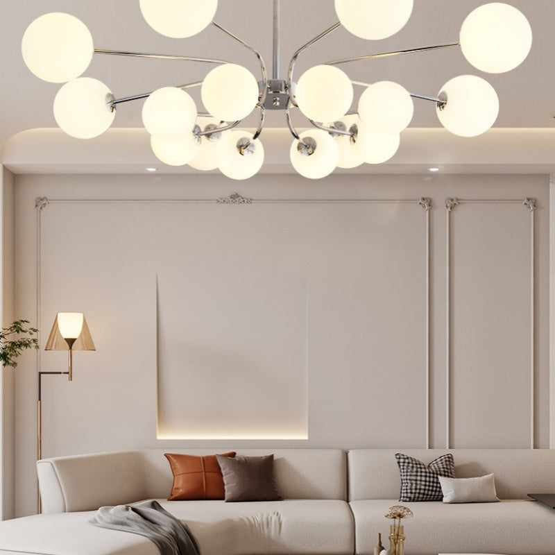 This Clérachic chrome sputnik chandelier lights a wall-panelled lounge with a brass floor lamp and patterned cushions on the sofa.