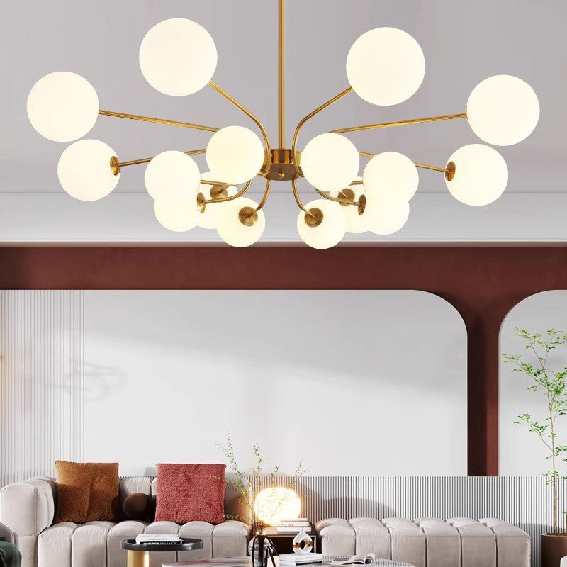The Clérachic sputnik chandelier in warm gold spans a living room with a dark arched doorway and a gold orb sculpture on the side table.