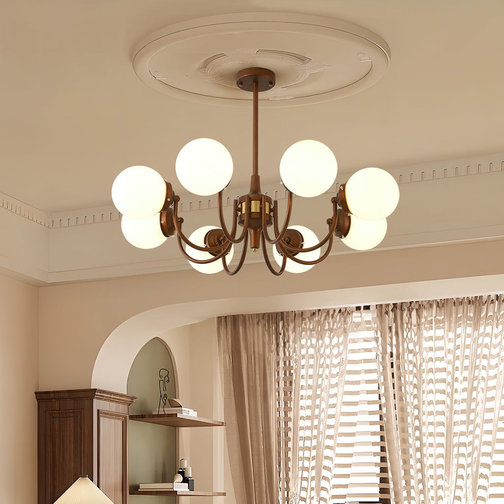 Eight white globes glow on this Clérachic chandelier, set below a plaster ceiling rose with pleated curtains and an arched alcove behind.