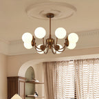 Eight white globes glow on this Clérachic chandelier, set below a plaster ceiling rose with pleated curtains and an arched alcove behind.