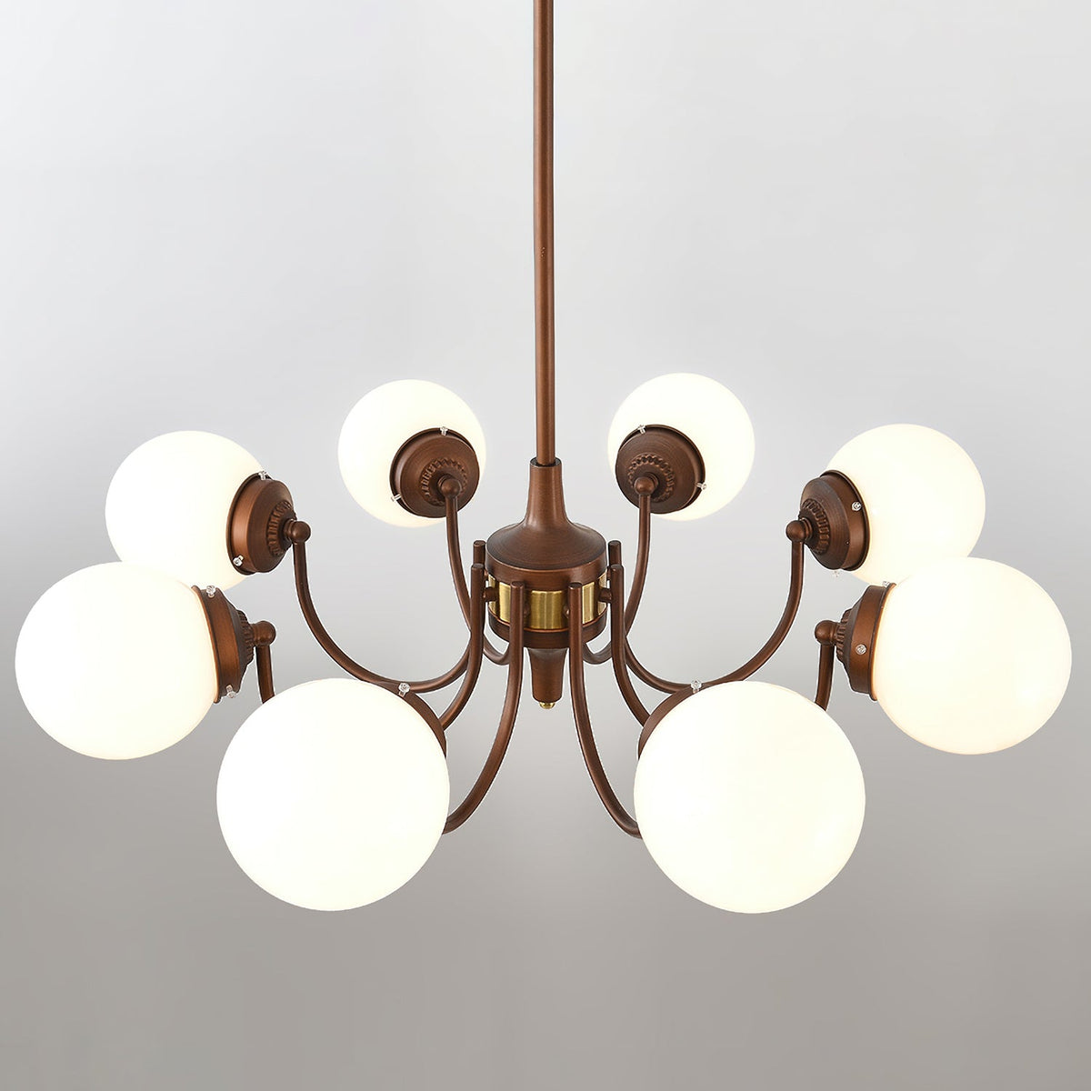 Underside view of the eight-light Clérachic chandelier, showing white globes on antique bronze arms with a brass band at the centre.