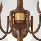 Close view of the brass band and curved bronze arms at the hub of this Clérachic chandelier.