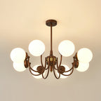 Eight-light Clérachic chandelier lit against a warm cream ceiling, its globes glowing around the bronze centre.