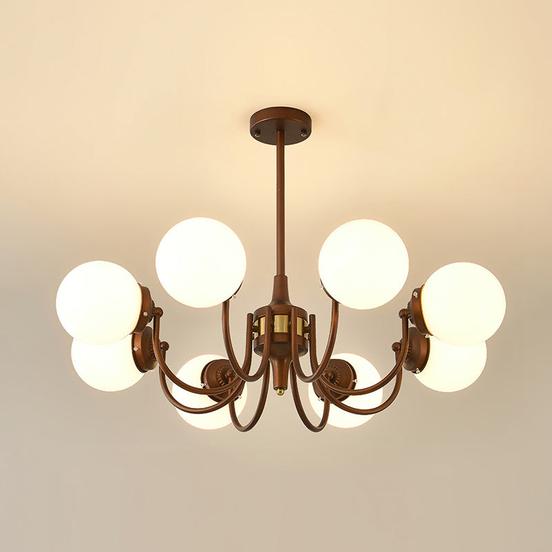Eight-light Clérachic chandelier lit against a warm cream ceiling, its globes glowing around the bronze centre.