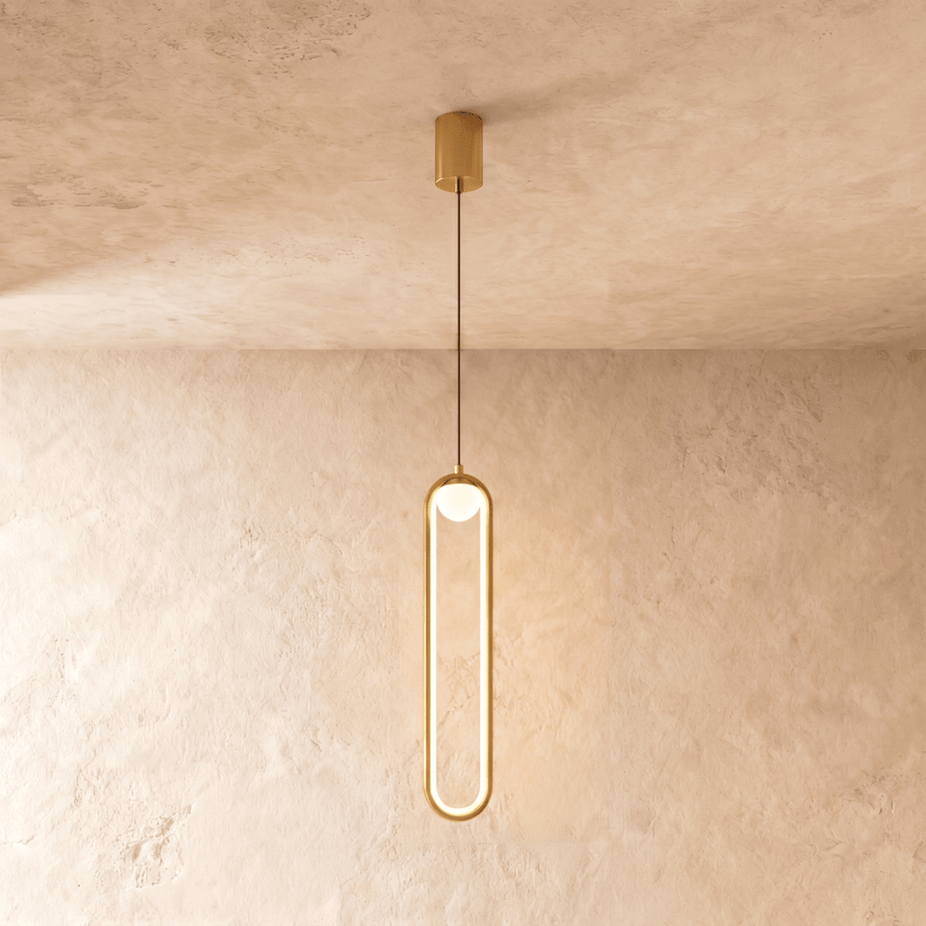 Clérachic slim gold stadium-shaped LED pendant light with a small white globe and gold canopy on a limewash wall.