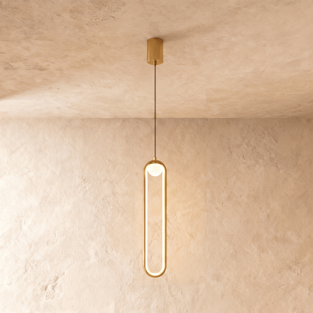 Clérachic slim gold stadium-shaped LED pendant light with a small white globe and gold canopy on a limewash wall.