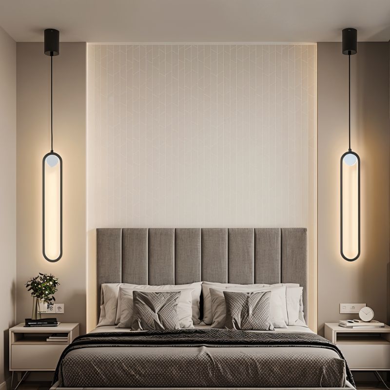 Clérachic pair of black stadium-shaped LED pendants hung either side of an upholstered bed with a grey headboard.