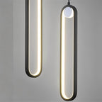 Close view of two Clérachic black stadium-shaped LED pendants, the glowing loops and small white globe against grey.
