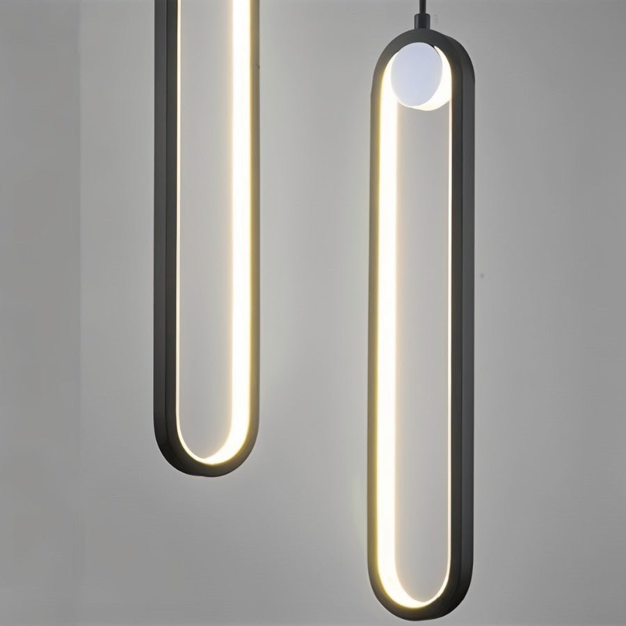 Close view of two Clérachic black stadium-shaped LED pendants, the glowing loops and small white globe against grey.