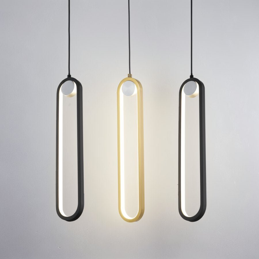 Clérachic black and gold stadium-shaped LED pendant lights side by side, the gold one lit, against a pale grey wall.