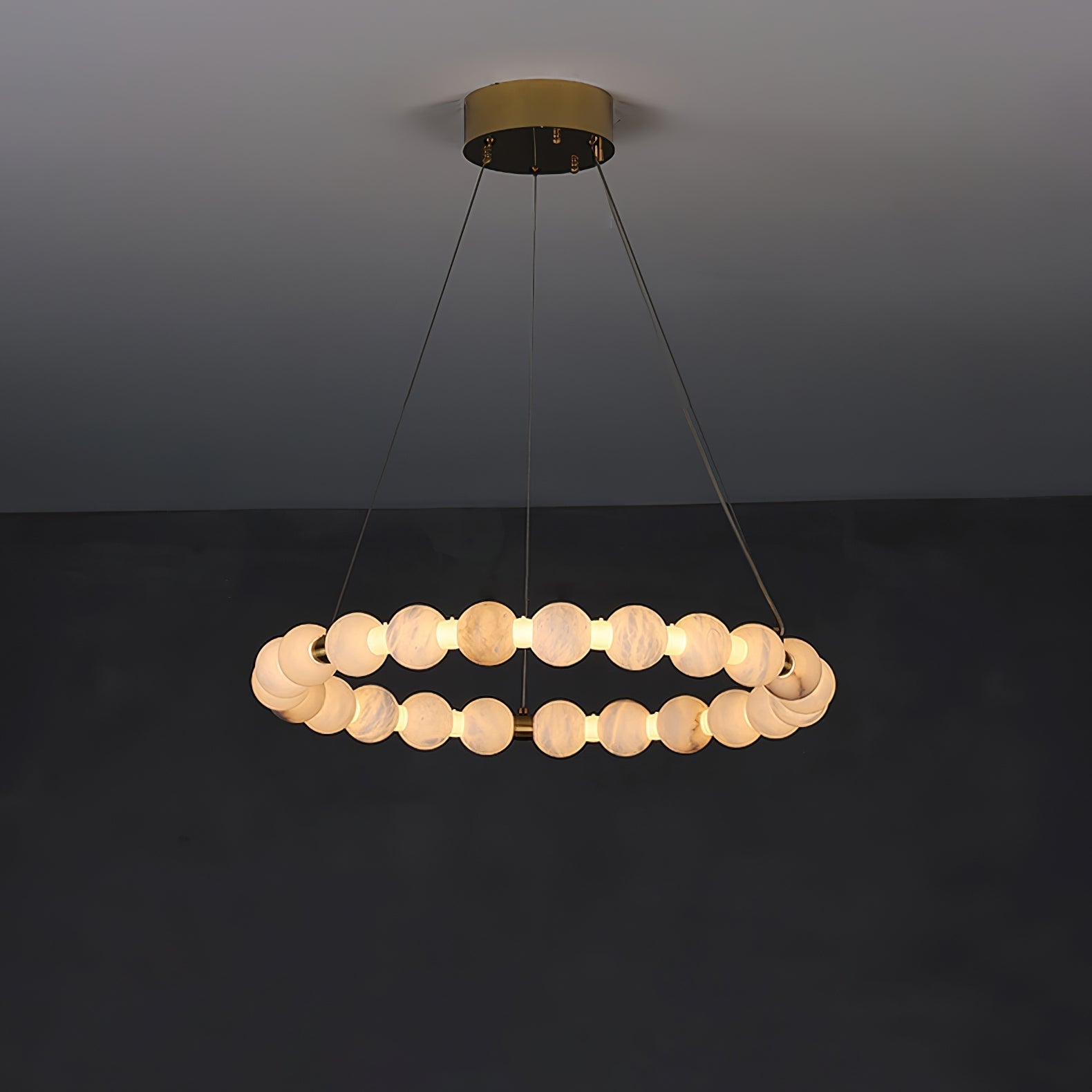 Clérachic Orb ring chandelier on a charcoal wall, a single ring of alabaster beads on brass.