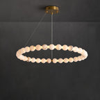 The Clérachic Orb ring chandelier lit against dark plaster, beads glowing evenly around it.