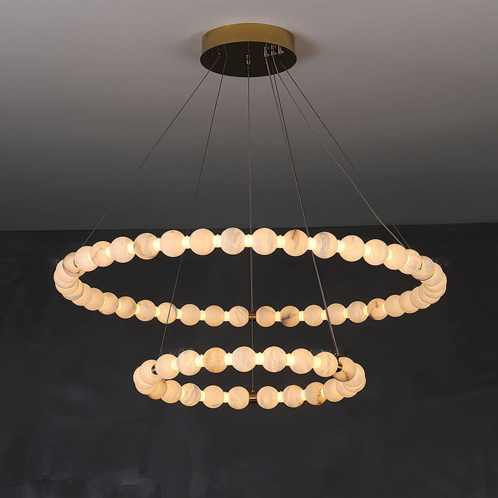 The Clérachic Orb chandelier with two stacked rings of alabaster beads on a brass canopy.