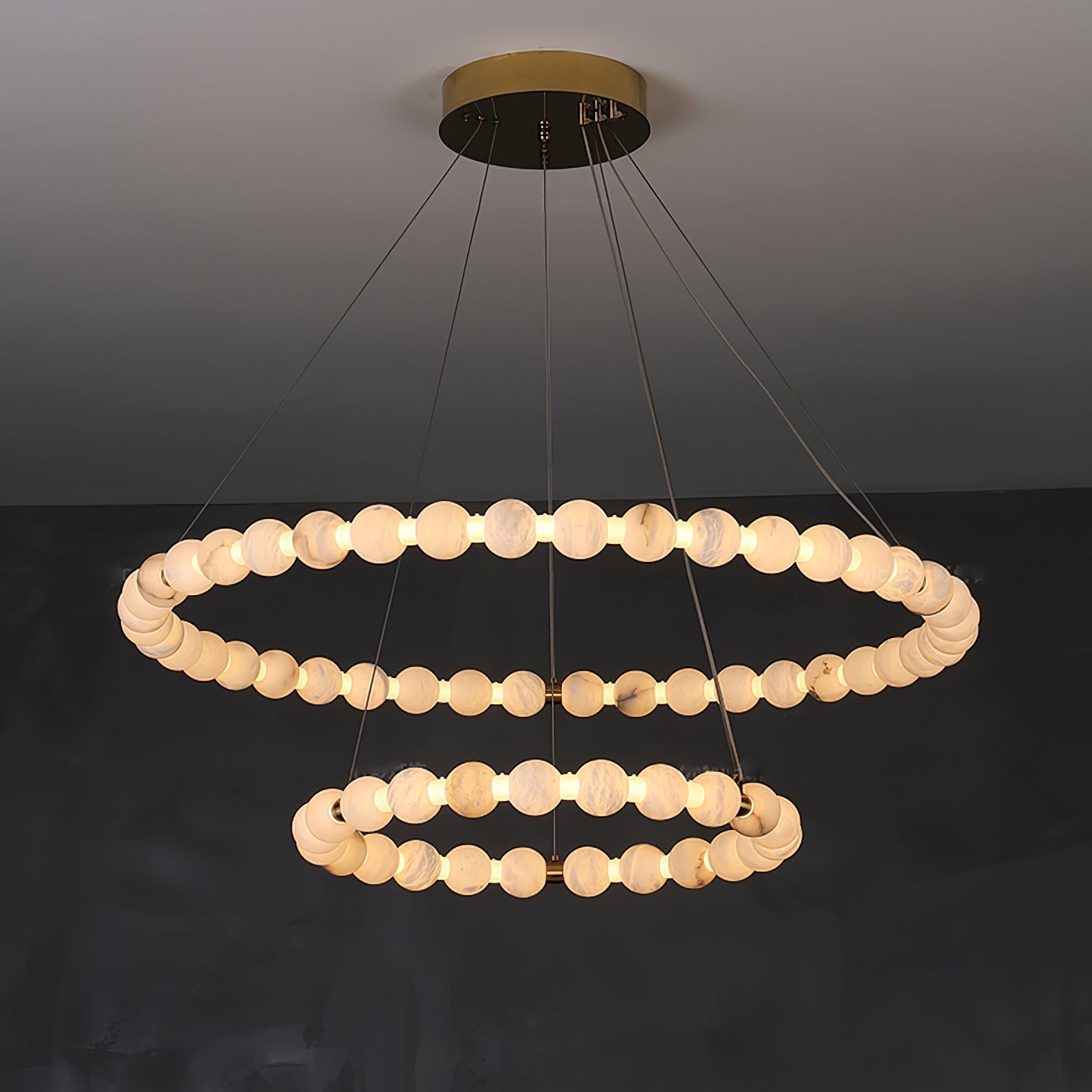 The Clérachic Orb chandelier with two stacked rings of alabaster beads on a brass canopy.