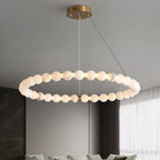 The Clérachic Orb chandelier lit above a living room with sheer curtains and a low sofa.