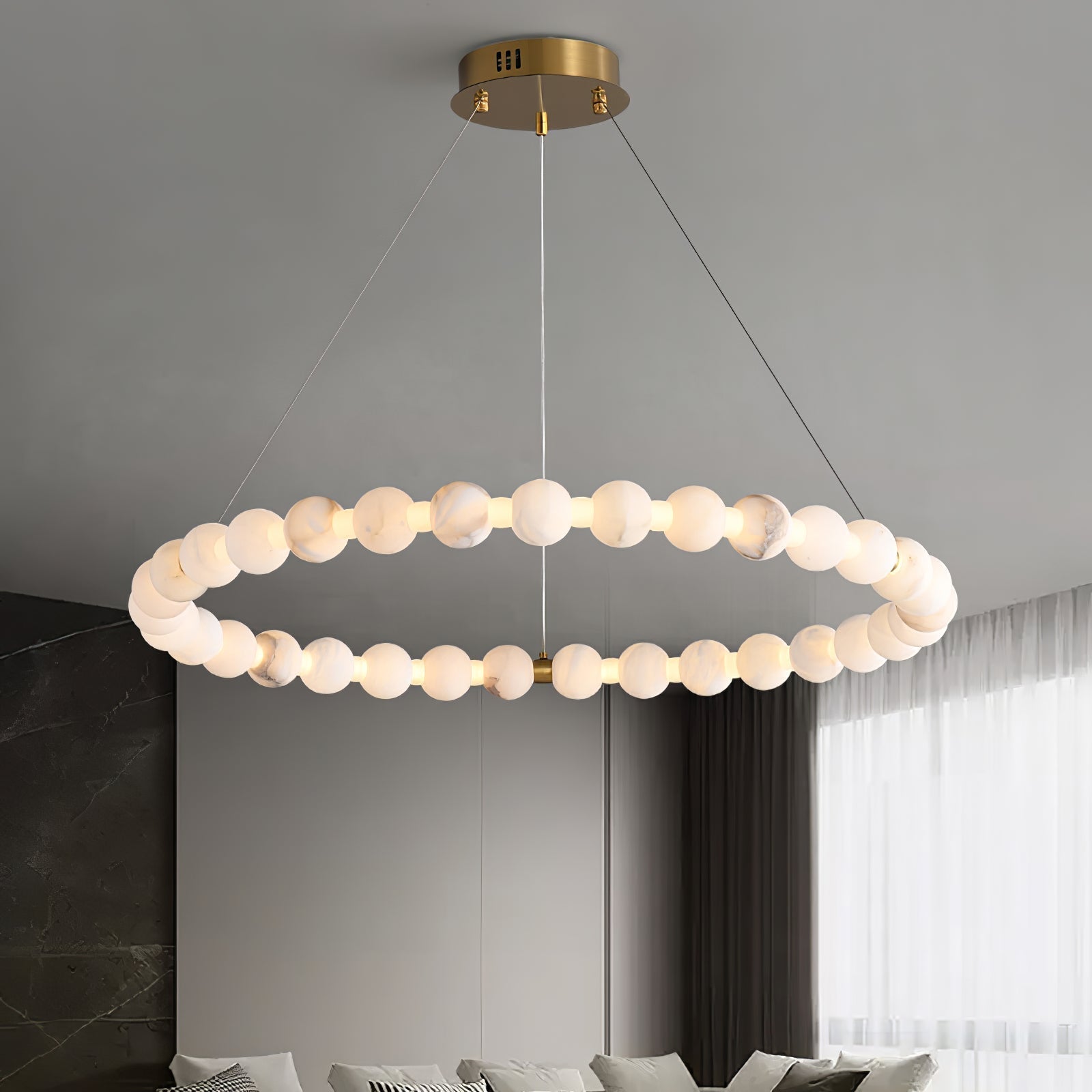 The Clérachic Orb chandelier lit above a living room with sheer curtains and a low sofa.