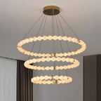 Clérachic Orb chandelier in three tiers, hung beside floor-length curtains in a pale room.