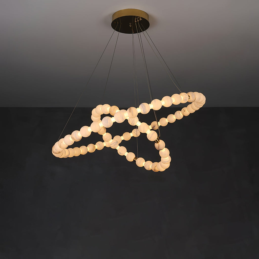 The Clérachic Orb chandelier spiralling on dark plaster, beads catching warm light.