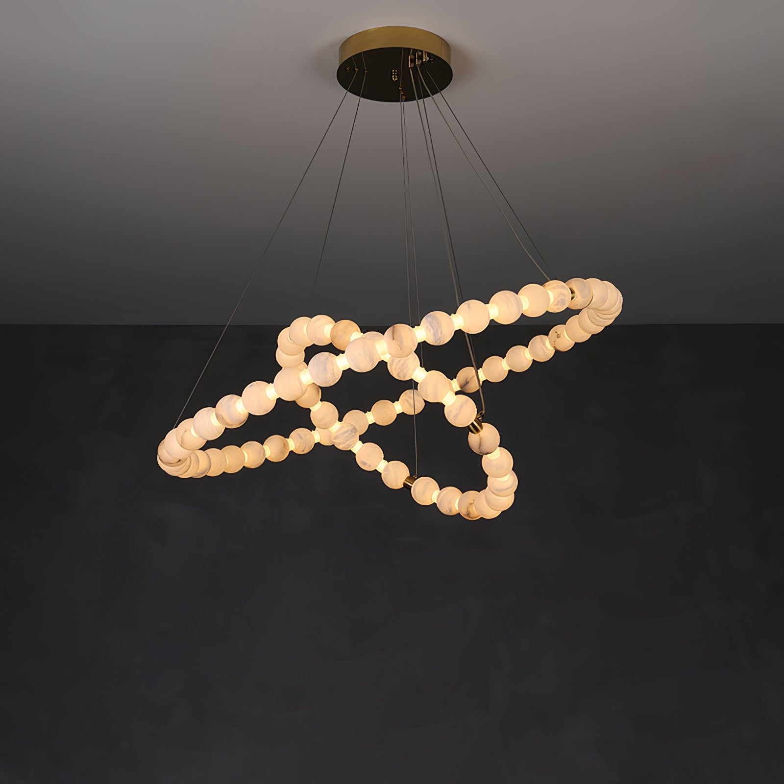 The Clérachic Orb chandelier spiralling on dark plaster, beads catching warm light.