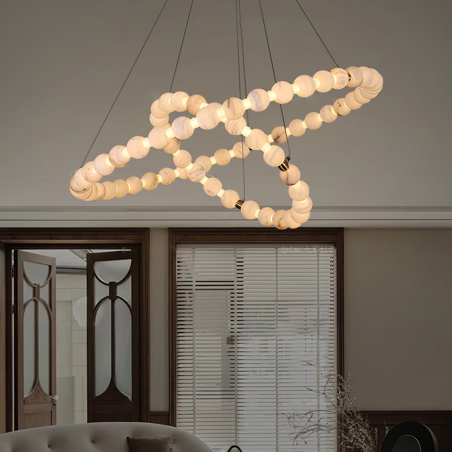 Clérachic Orb chandelier spiralling above a living room with glazed doors and blinds.