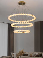 Clérachic Orb chandelier in three tiers above a beige lounge with sheer drapes.