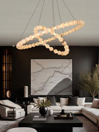 Clérachic Orb chandelier hanging over a dark living room with a marble artwork behind.