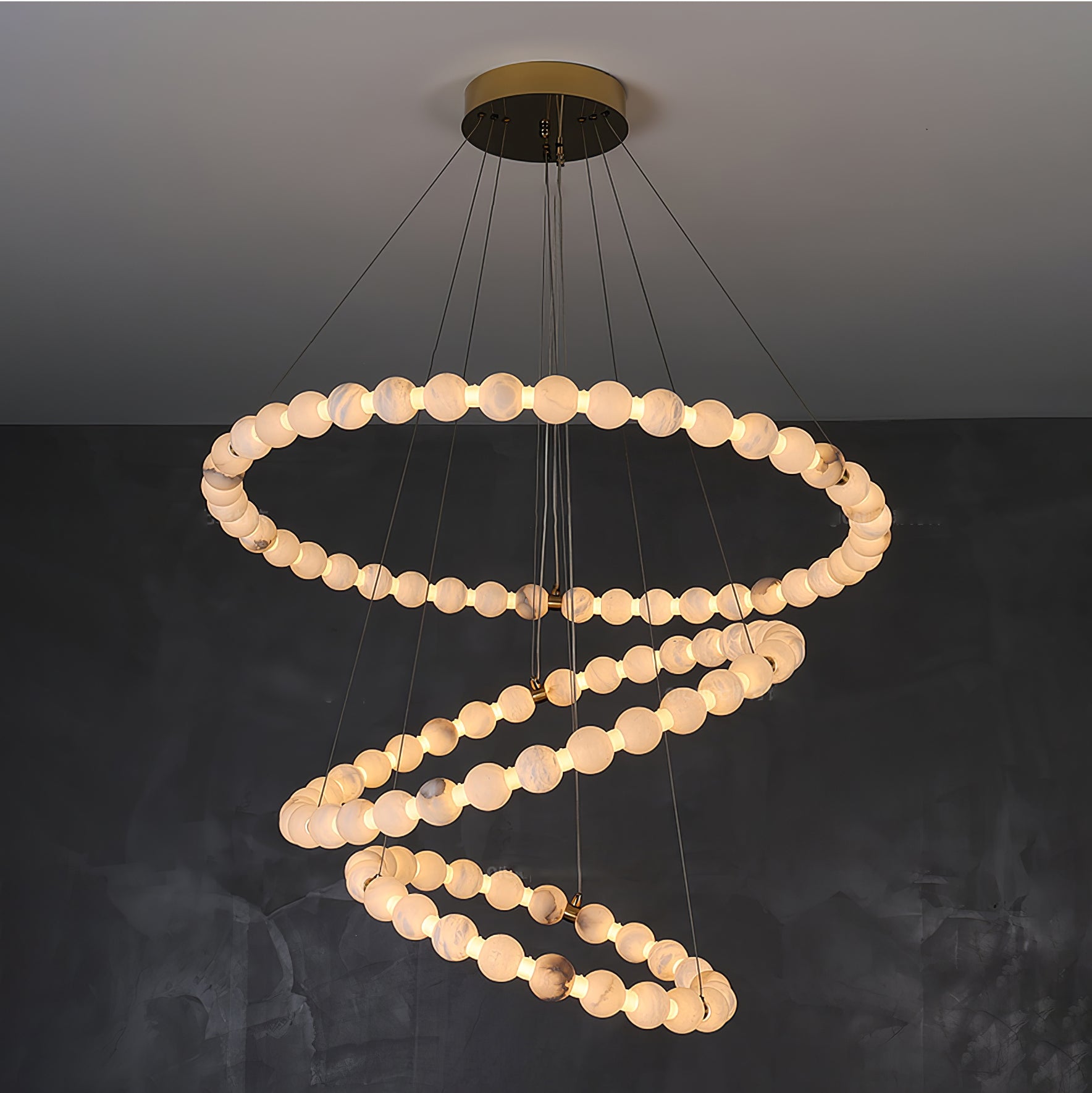 Clérachic Orb chandelier in a wide spiral on charcoal, cables fanning from the brass canopy.