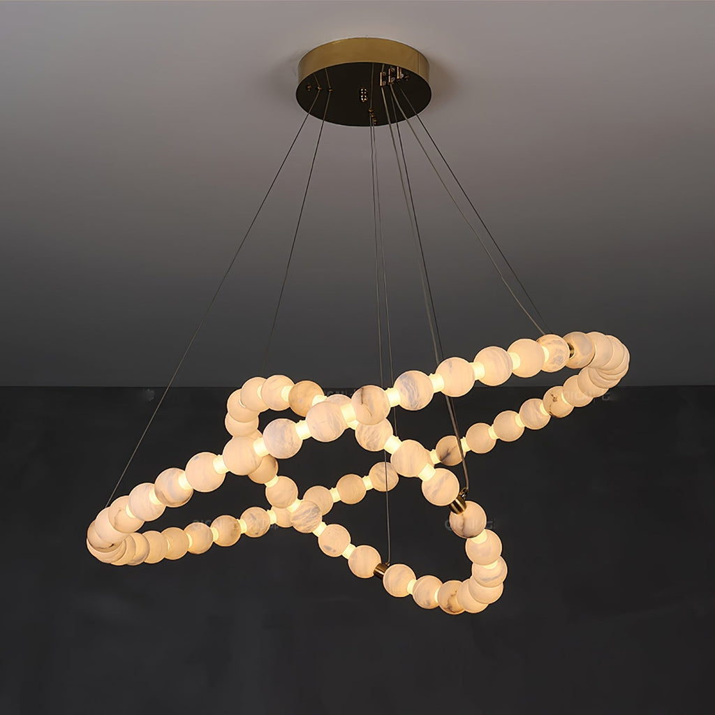 The Clérachic Orb chandelier spiralling on grey, warm beads set against the dark wall.