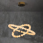 Clérachic Orb chandelier in a compact spiral against textured grey plaster.