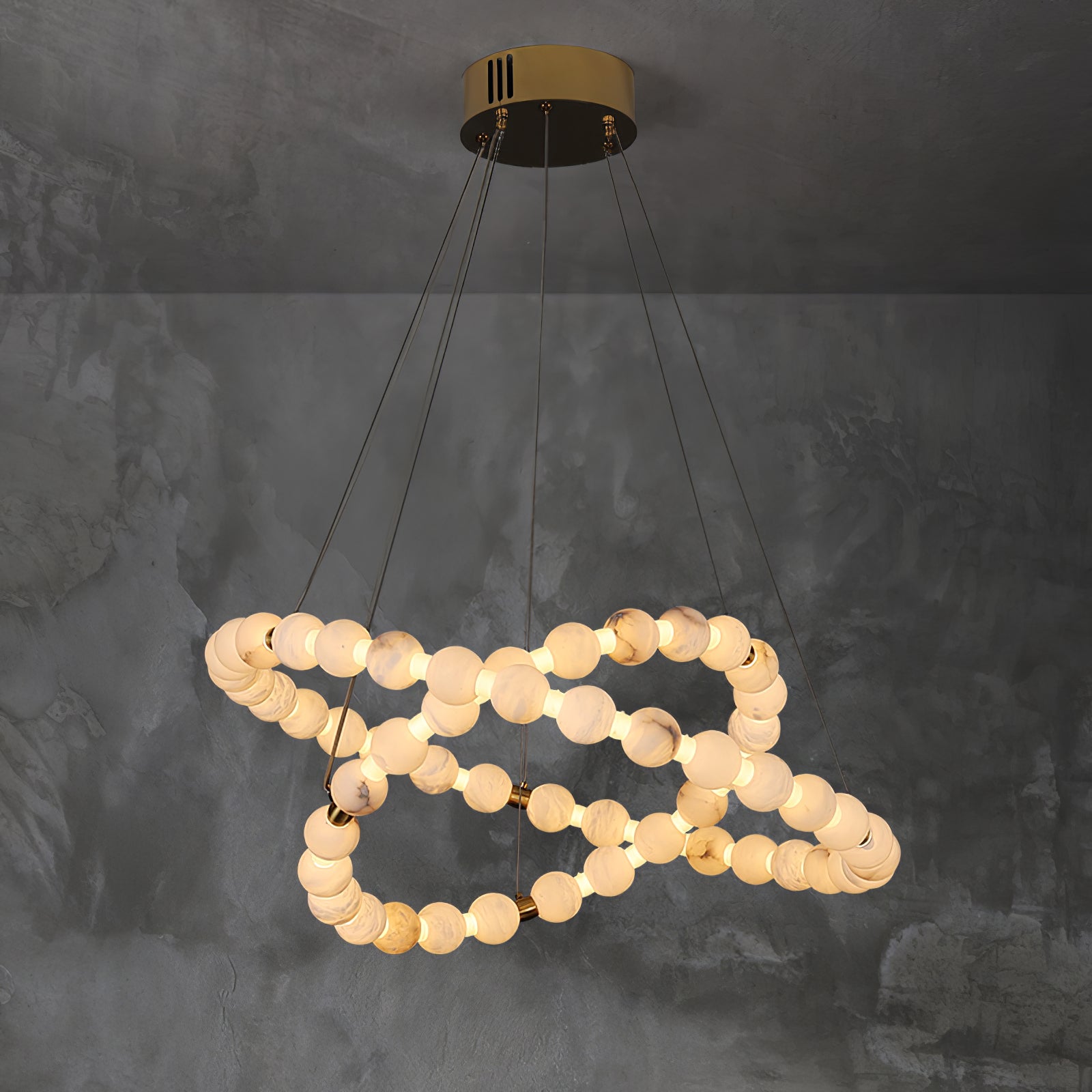 Clérachic Orb chandelier in a compact spiral against textured grey plaster.