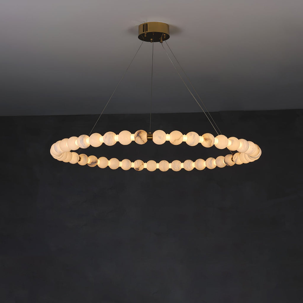 Clérachic Orb ring chandelier lit wide on a dark wall, brass canopy flush to the ceiling.