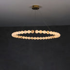Clérachic Orb ring chandelier lit wide on a dark wall, brass canopy flush to the ceiling.