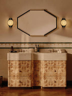 Two Clérachic Orb sconces flanking an octagonal mirror above a burl-wood double vanity.