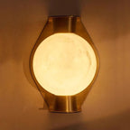Clérachic Orb sconce in brass finish, glowing globe centred on the tapered backplate.