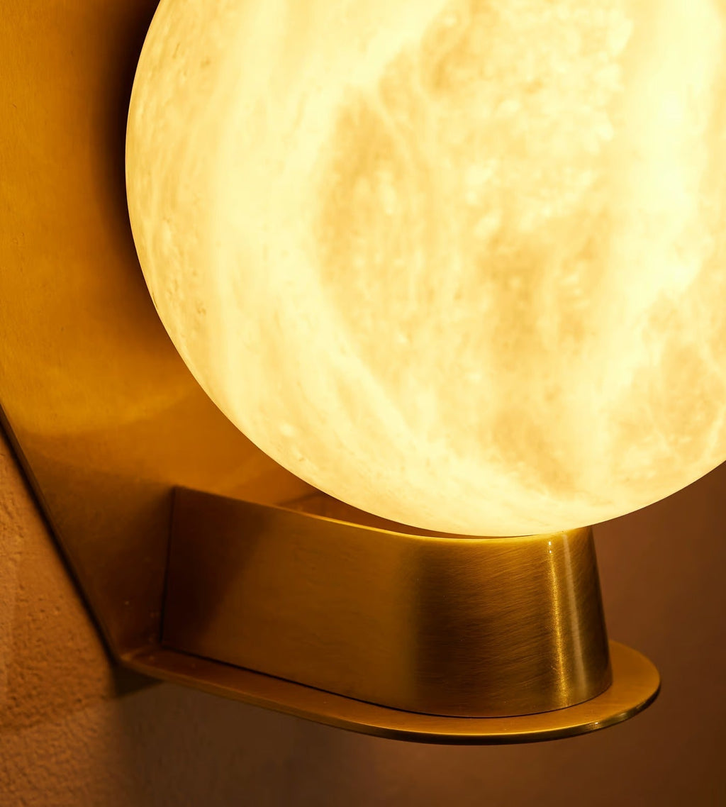 Macro of the Clérachic Orb globe, veined alabaster lit warm above the brushed metal base.