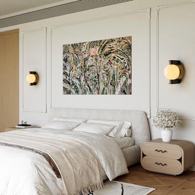 A pair of Clérachic Orb sconces either side of botanical art above a linen-dressed bed.