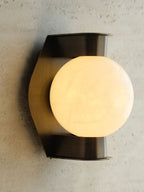 The Clérachic Orb sconce angled on rough plaster, warm light raking across the wall.