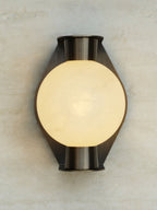 Clérachic Orb sconce lit on a travertine wall, an even amber glow through the stone sphere.