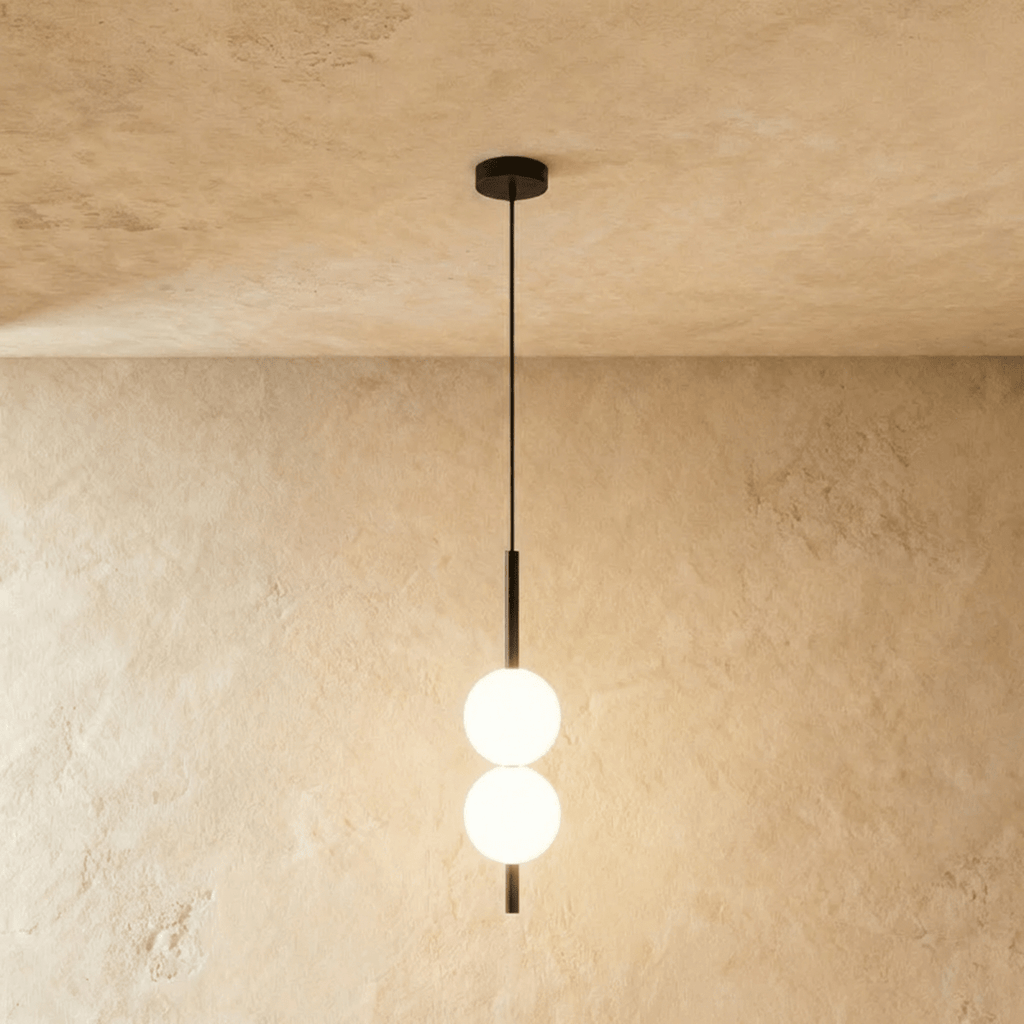 Clérachic two-ball orb pendant light in a matte black finish, both globes glowing warm on one slim rod.